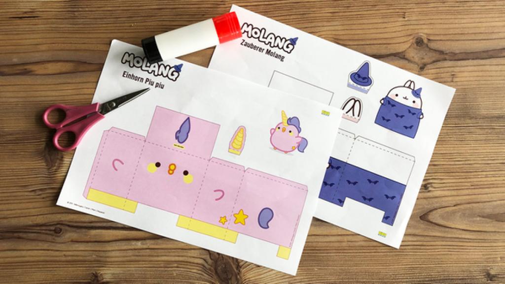 Eine Bastelvorlage für Molang-Figuren, Schere, Kleber auf einem Holztisch