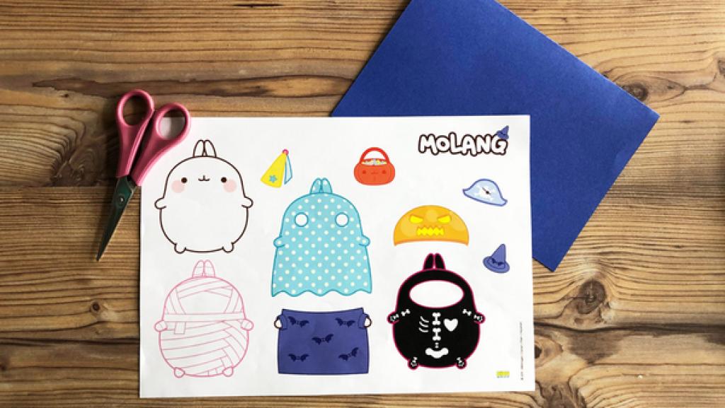 Eine Bastelvorlage, eine Schere und blaues Bastelpapier auf einem Holztisch.