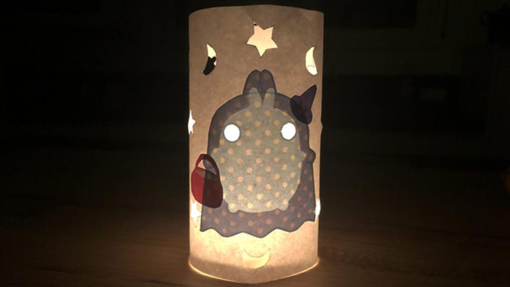 Das Windlicht im Dunkeln mit einer angezündeten Kerze.