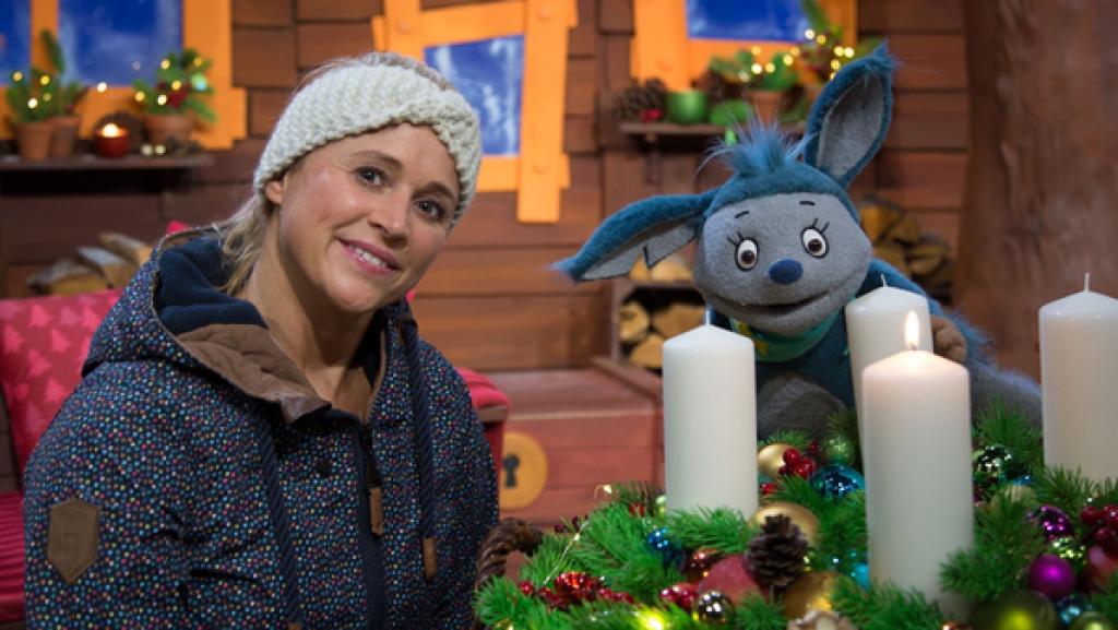 Die erste Kerze am Adventskranz wird angezündet. Fidi ist fasziniert und hat allerlei Fragen zu diesem Brauch.