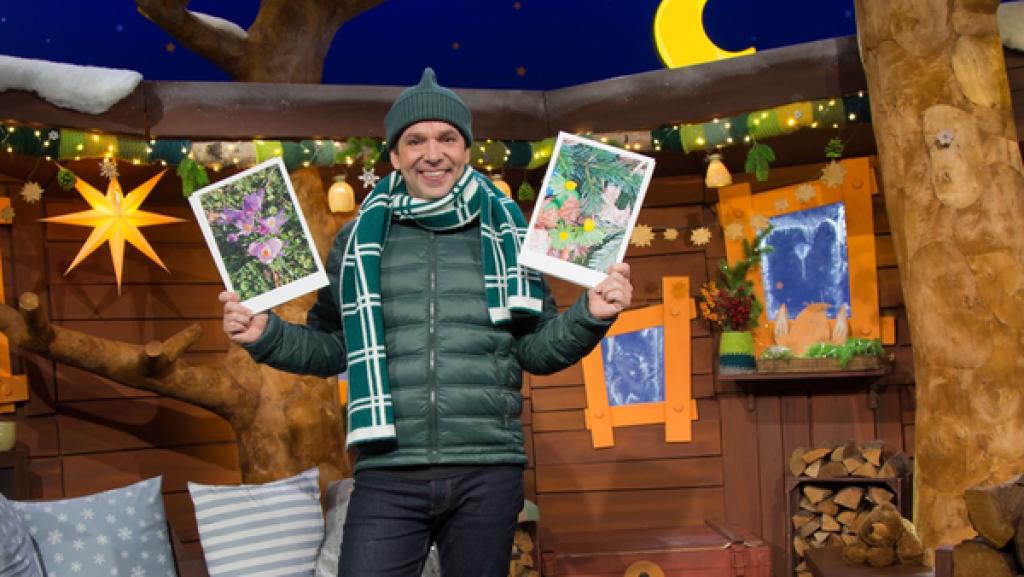 Juri zeigt Winterlinge. Das sind leuchtende gelbe Blumen.