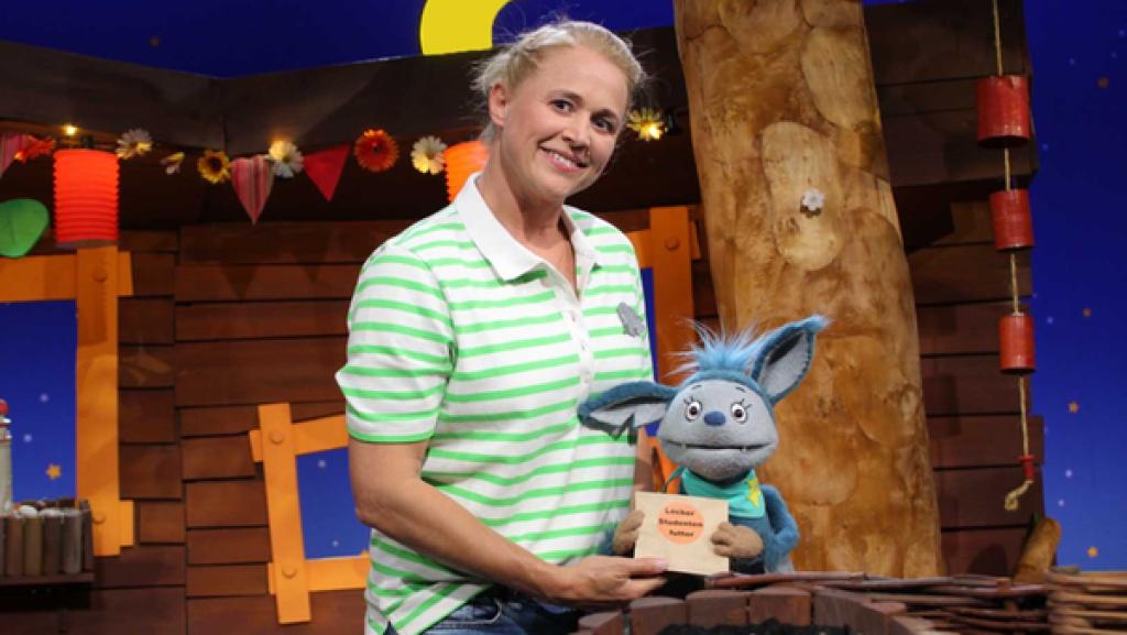 Fidi und Singa spielen Einkaufen. Fidi ist die Verkäuferin, und Singa möchte eine Tüte Futterstudenten kaufen.