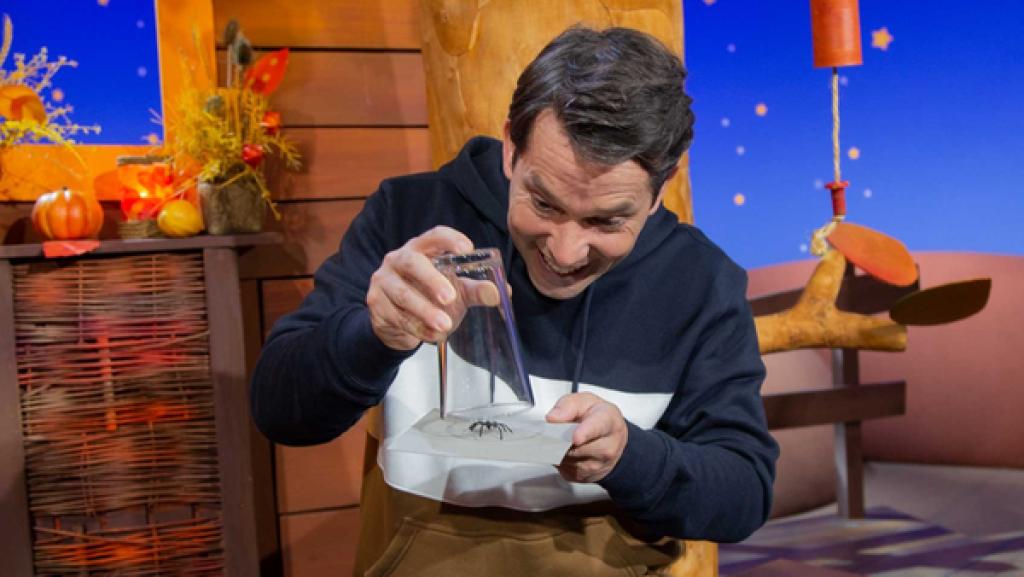 Juri demonstriert, wie man mit einem Wasserglas eine Spinne nach draußen befördern kann.
