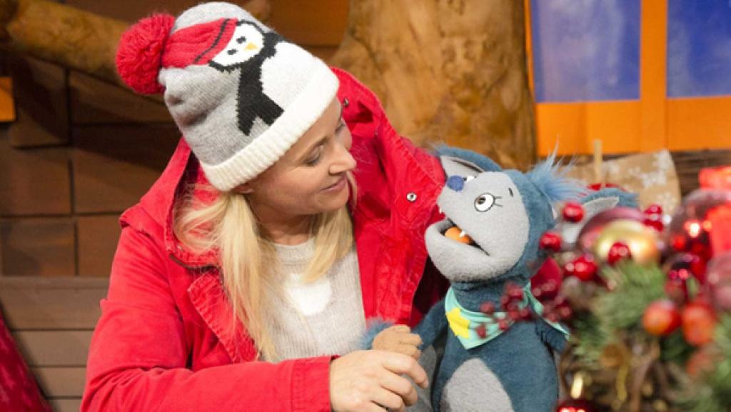 Singa und Fidi lächeln sich an. Vor ihnen steht ein Xylophon, auf dem Weihnachtsplätzchen liegen.