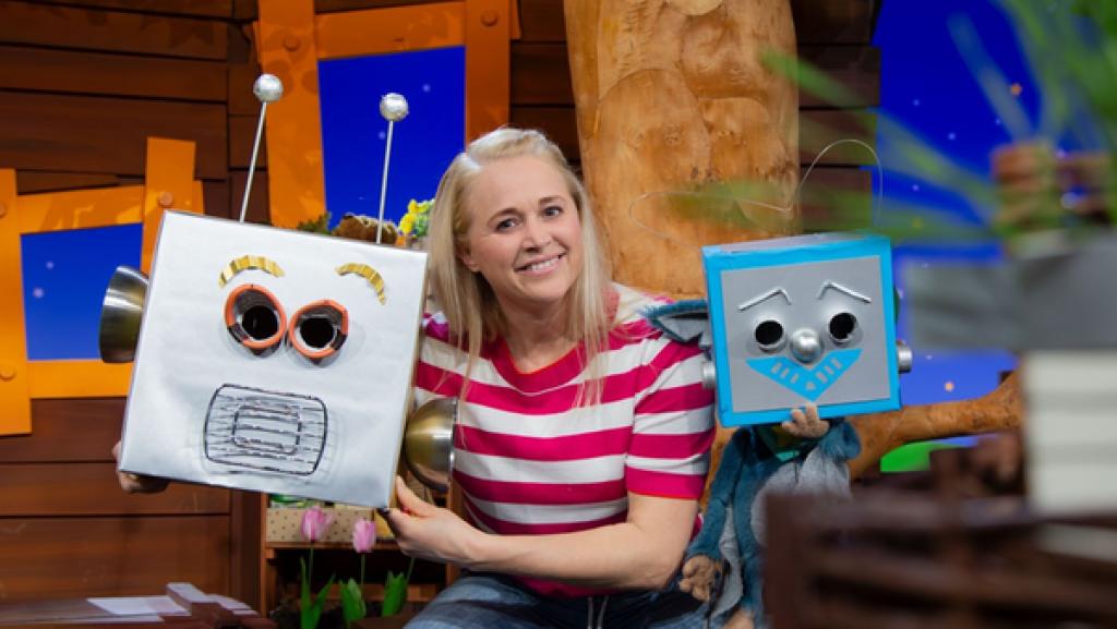 Rechte: KiKA Singa hat ein Roboterkopf in der Hand. Neben ihr ist Fidi, die einen gebastelten Roboterkopf trägt.