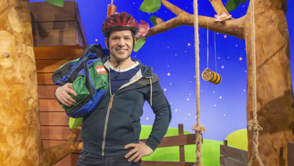 Rechte: KiKA Juri trägt einen roten Fahrradhelm. Über seiner Schulter hängt ein bunter Fahrradrucksack.