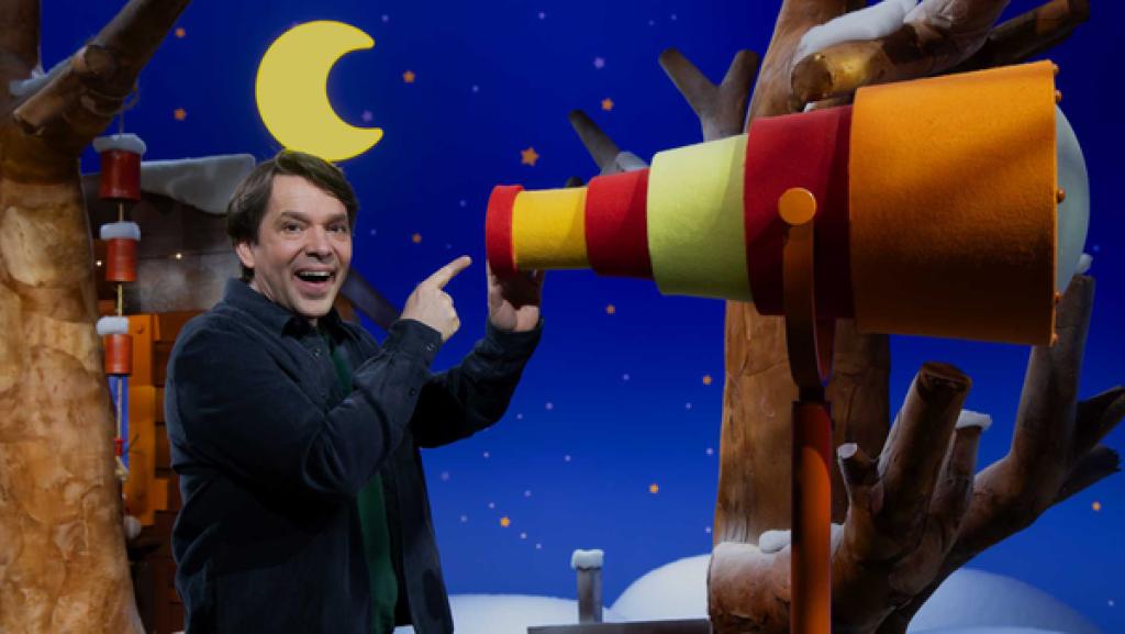 Juri steht am Fernrohr und zeigt darauf.