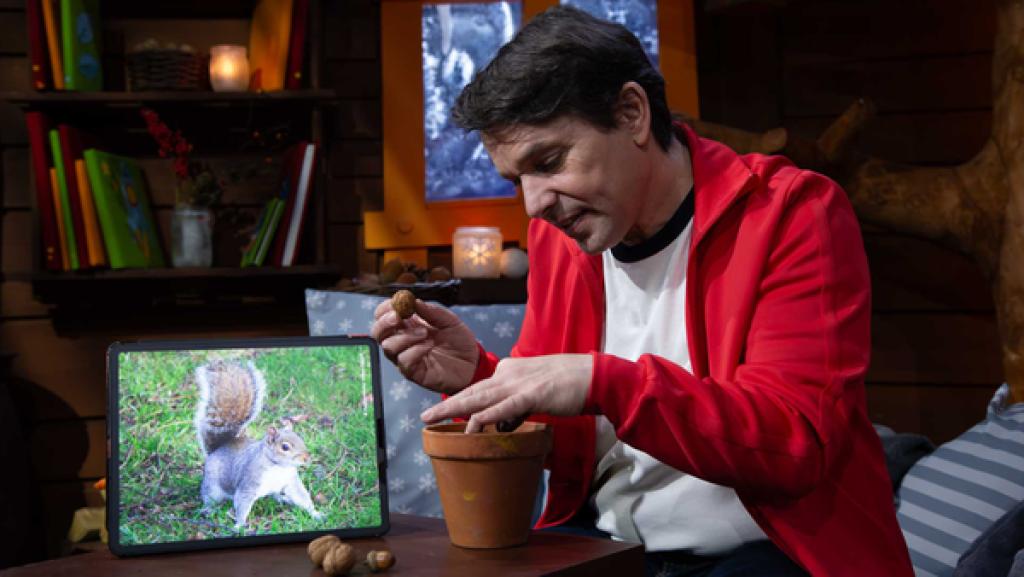 Juri holt eine Walnuss aus einem Blumentopf. Danaben steht ein Bild eines Eichhörnchens.