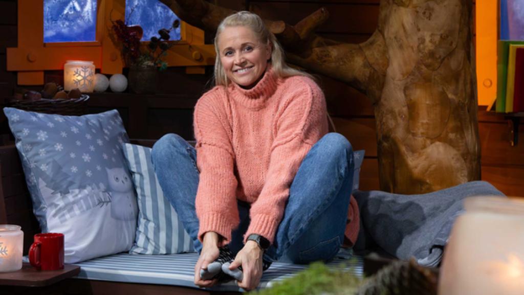 Singa sitzt lächelnd im Baumhaus und wärmt ihre Füße mit den Händen.