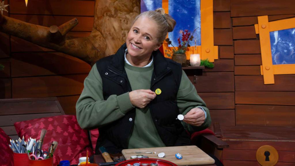 Singa sitzt auf dem Sofa und bastelt Buttons, die sie sich an ihre Weste dranhält.