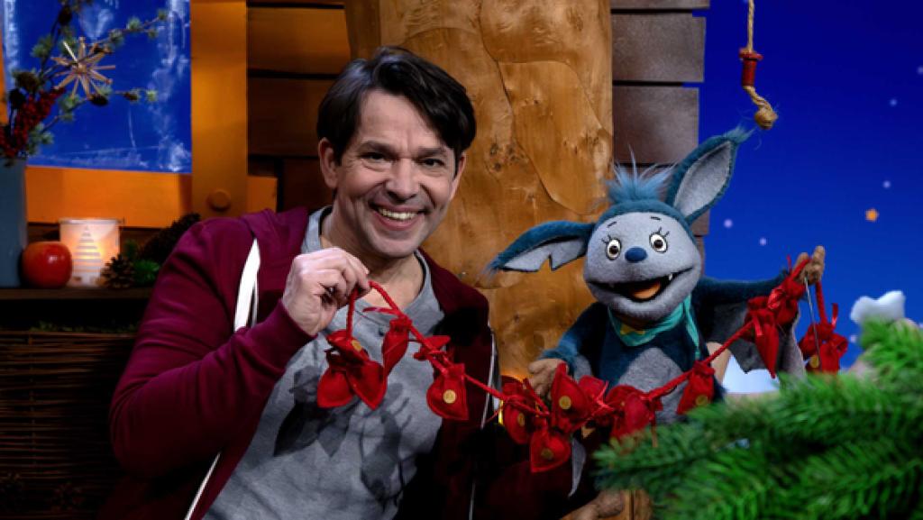 Fidi und Juri halten ein Band mit roten Säckchen in der Hand und lachen.