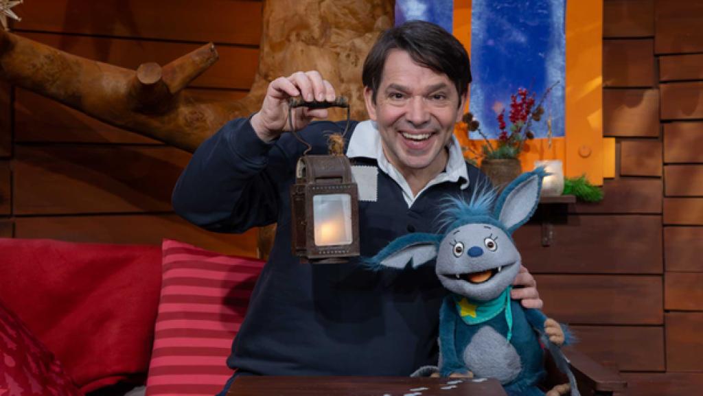 Fidi und Juri sitzen lachend im Baumhaus. Juri hält eine kleine Laterne.