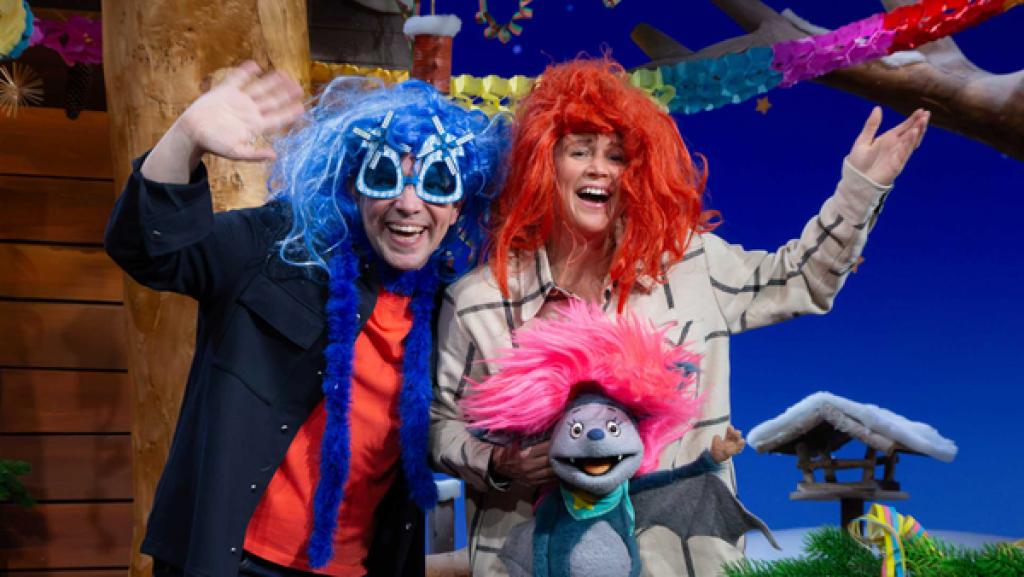 Fidi, Singa und Juri tragen lustige, bunte Perücken und jubeln im bunt geschmückten Baumhaus.