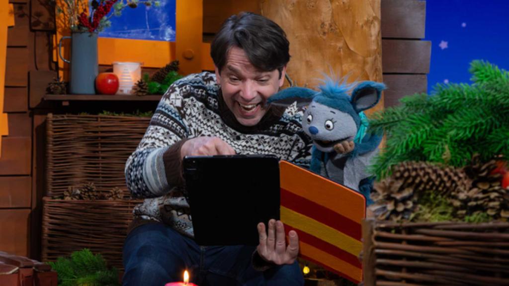 Fidi und Juri sitzen am Baum. Sie schauen gemeinsam auf das Tablet und lachen.