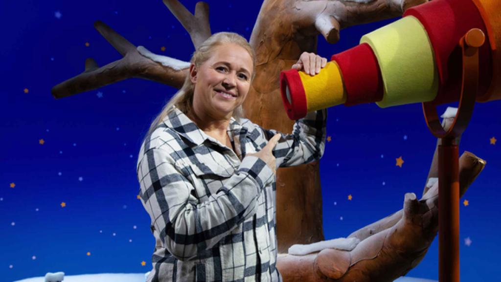 Singa steht am Fernrohr und zeigt mit dem Finger in das Guckloch.