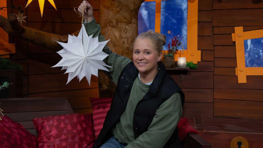 Singa sitzt auf dem Sofa und hält einen Stern aus Papier neben ihren Kopf.