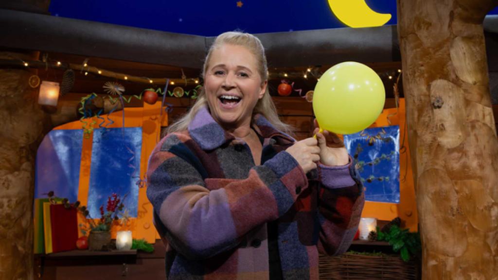 Singa steht im Baumhaus. In ihrer Hand hält sie einen gelben Luftballon.