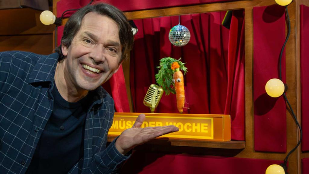 Juri steht im Baumhaus links neben einem Puppentheater. Im Theater ist das Gemüse Kai Karotte.