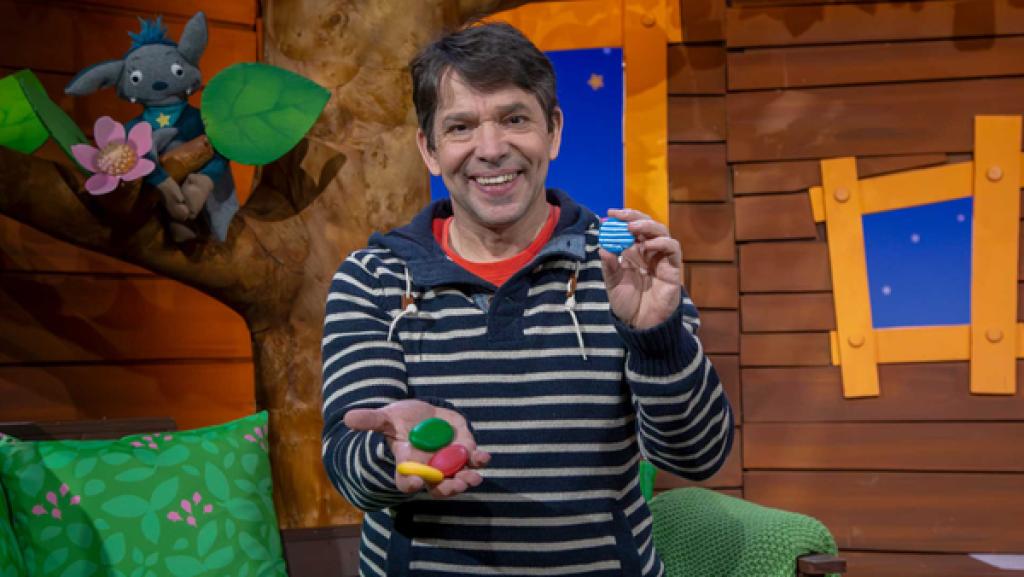 Juri sitzt im Baumhaus und zeigt seine bunten, selbstbemalten Steine.