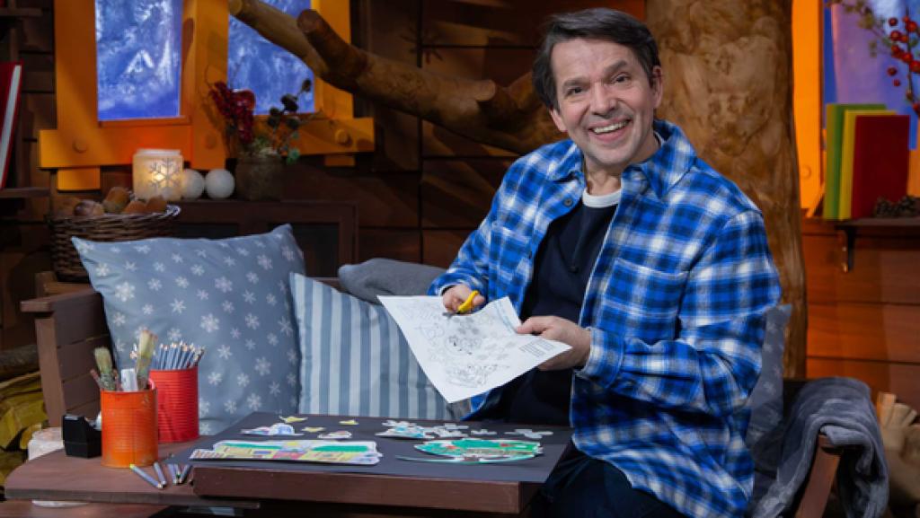 Juri sitzt im Baumhaus und legt lachend die MACHMiT!-Fensterbilder vor sich zusammen.