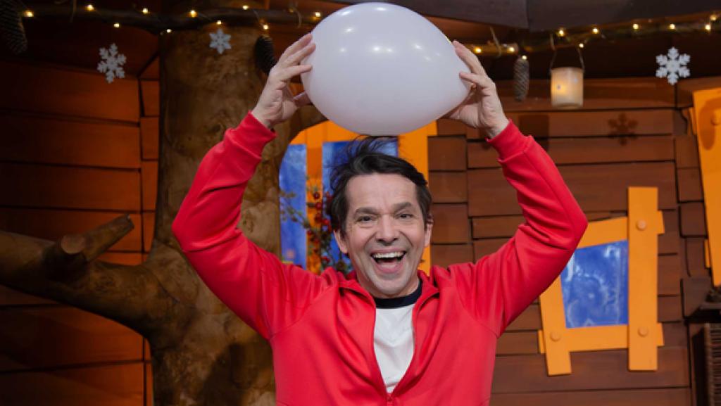 Juri sitzt lachend im Baumhaus und hält sich einen Luftballon über den Kopf. Seine Haare stehen ab.