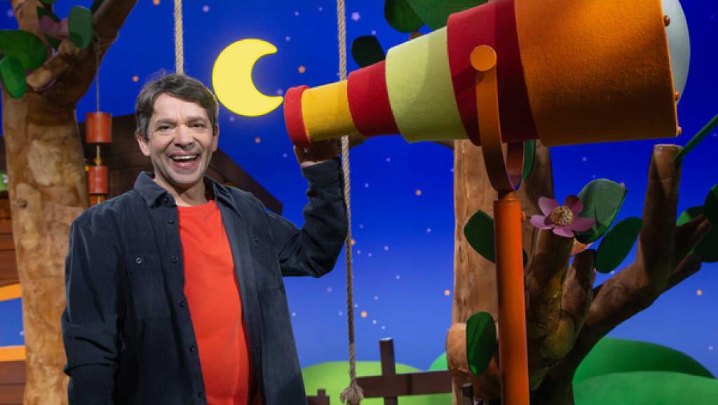 Juri steht am Fernrohr und lacht.