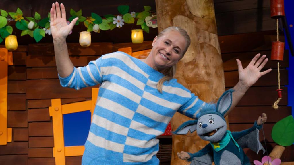 Singa und Fidi stehen im Baumhaus und strecken ihre Arme zur Seite. Sie lachen beide.