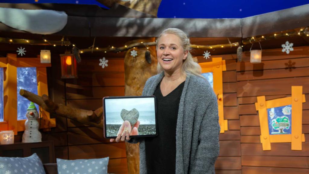 Singa zeigt ein Bild auf ihrem Tablet, auf dem ein herzförmiger Stein zu sehen ist.