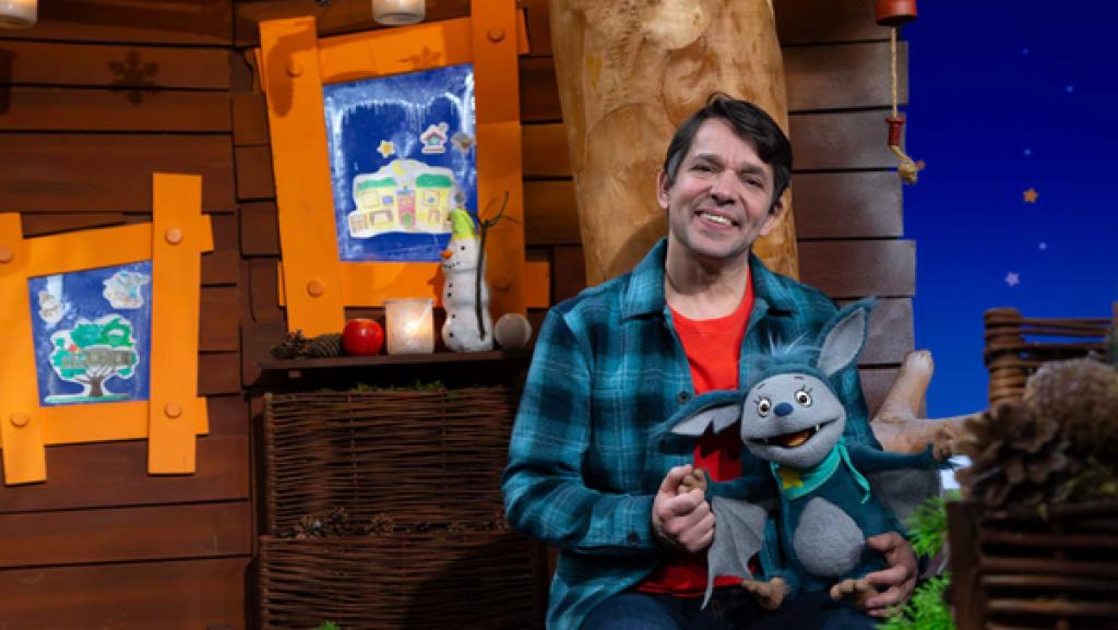 Fidi und Juri sitzen auf einer Bank im Baumhaus und lächeln.