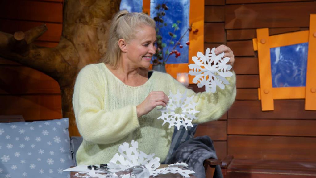 Singa sitzt im Baumhaus und zeigt ihre selbstgebastelten Schneeflocken.