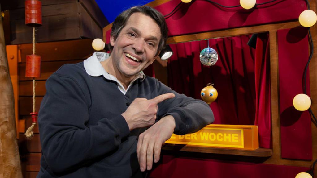 Juri steht neben dem Theater im Baumhaus. Im Theater ist Zilly Zwiebel zu sehen.