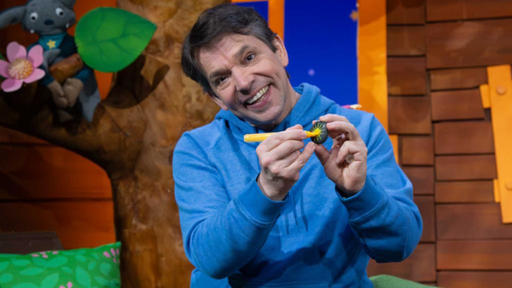 Juri sitzt im Baumhaus und malt auf einen Stein eine Sonne.