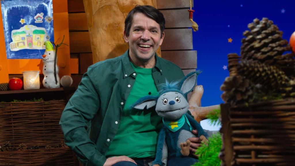 Fidi und Juri sitzen auf der Bank im Baumhaus und lächeln.