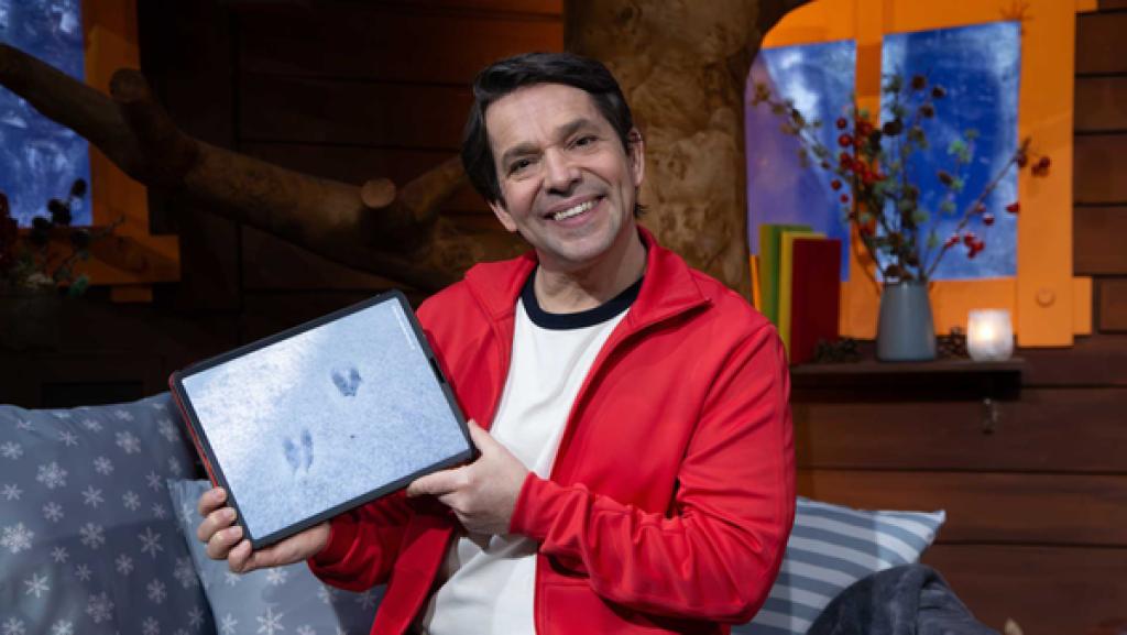 Juri hält das Tablett in der Hand. Es zeigt ein Bild von Tierspuren im Schnee.