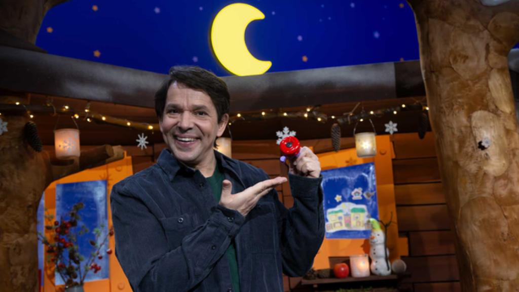 Juri steht im Baumhaus und zeigt auf seine rote Klingel.