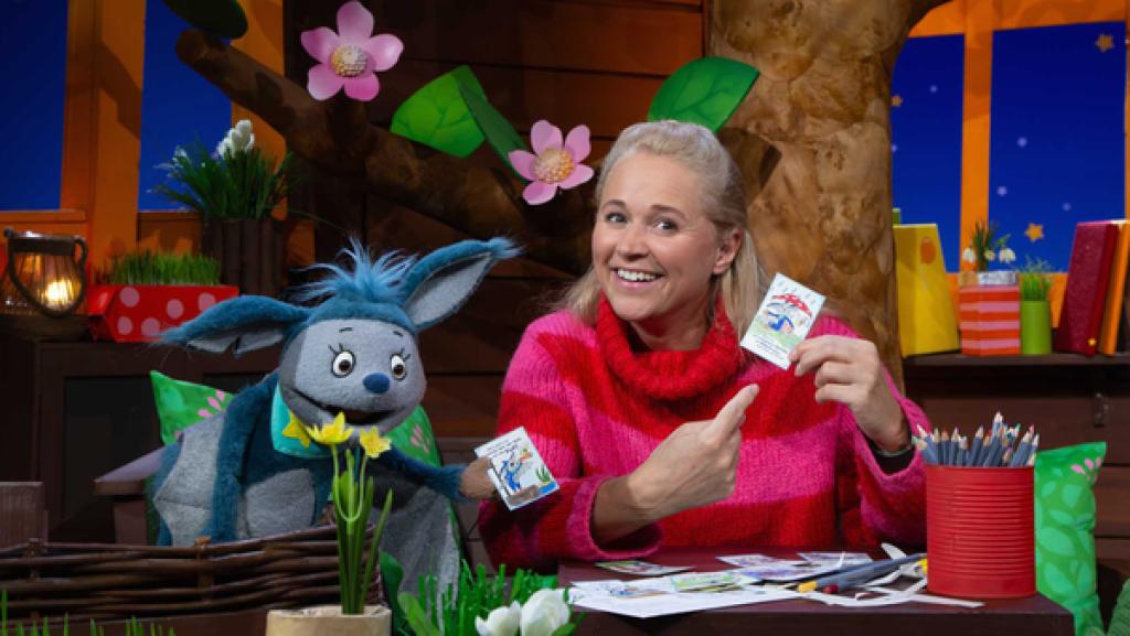 Singa und Fidi sitzen im Baumhaus. Sie halten Mutmachkarten in der Hand und lachen.