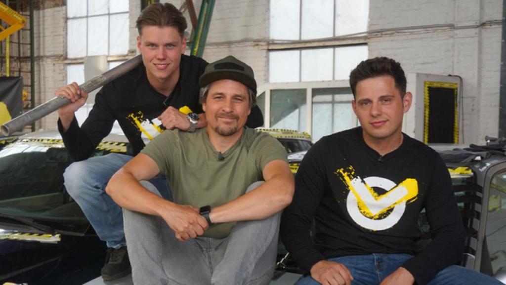 Checkpoint: Moderator Tommy Scheel, Jeppe und Cem sitzen auf einem Auto. 
