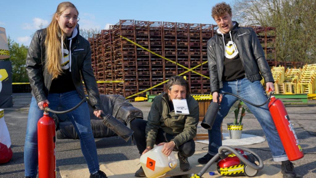 Raketenbike, Schmiede und ein feuriger Sauger | Rechte: ZDF Checkpoint: Tommy Scheel und Laura und Kenneth hocken um einen Teppich, auf dem ein Staubsauger und ein Benzinkanister platziert sind. Laura und Kenneth halten Feuerlöscher, alle schauen erschreckt-erwartungsvoll.