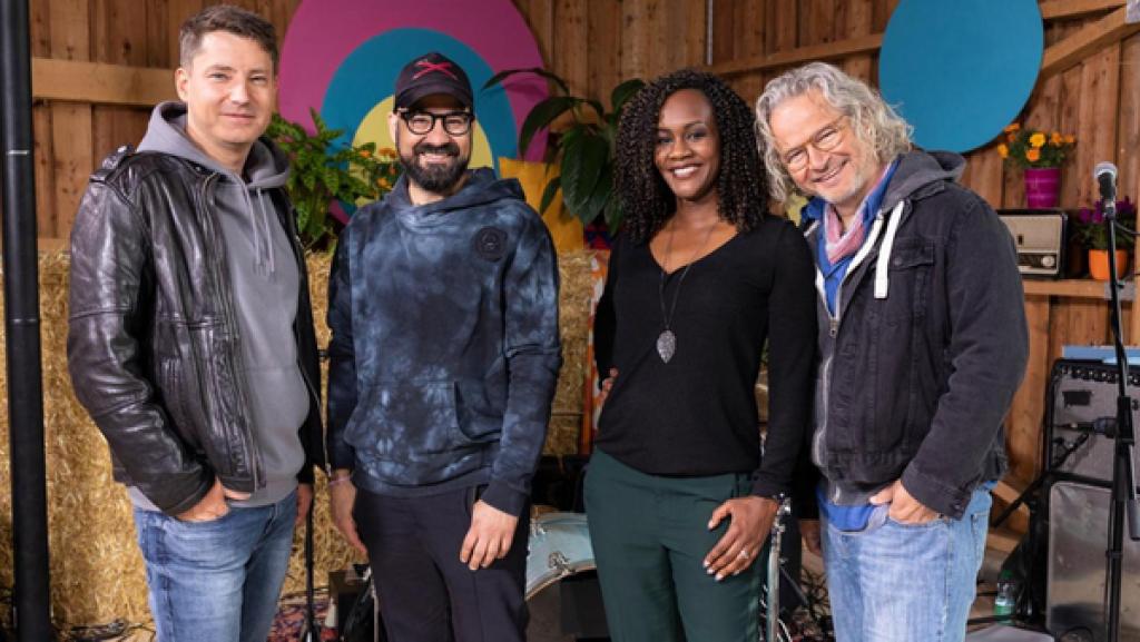 Die "Dein Song" Band (v.l.n.r) Daniel Stelter, Mario Garruccio, Sherita Owusu und Georg Göb stehen in der Scheune. Hinter ihnen Strohballen und ein Schlagzeug.