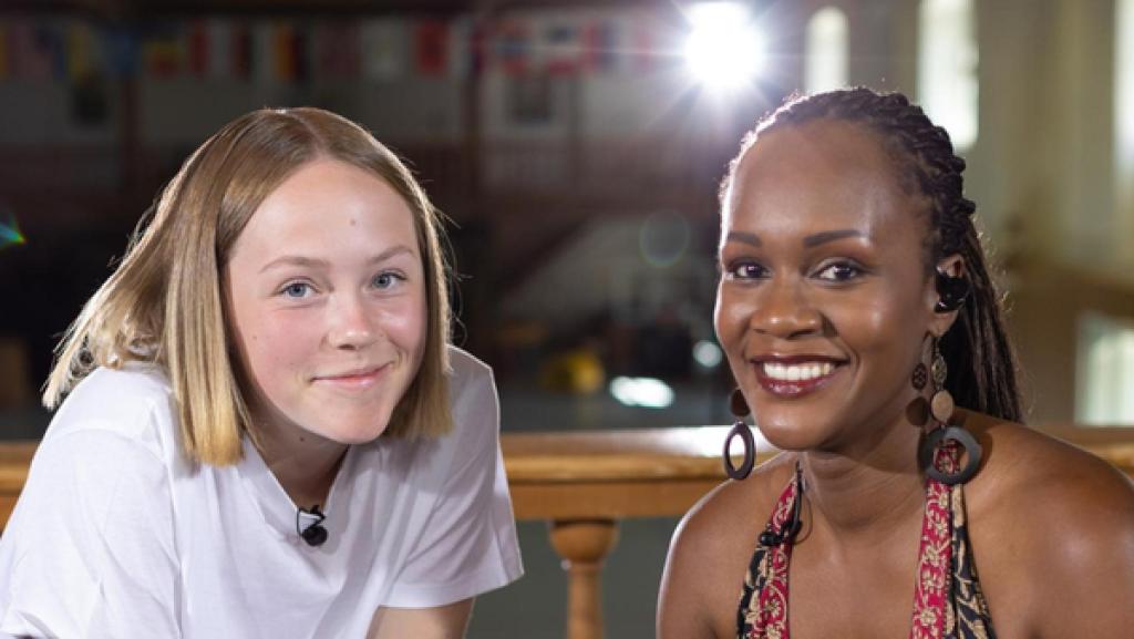 Kandidatin Maja (15) sitzt mit der Sängerin der „Dein Song“-Band auf der „Dein Song“-Probebühne. Die beiden lächeln freundlich in die Kamera.