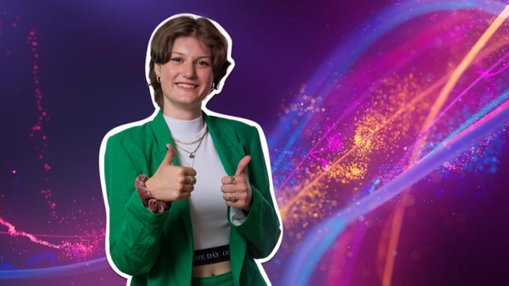 Mira hält beide Daumen nach oben und lächelt in die Kamera.