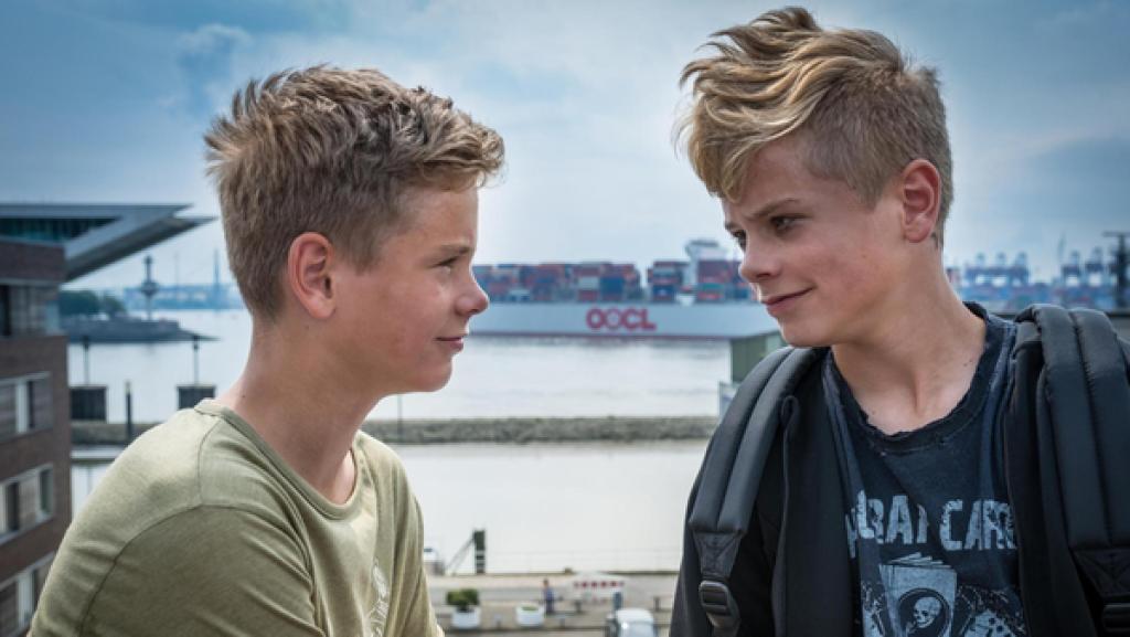 David (Luis Winter) und Marvin (Lewin Winter) stehen lächelnd am Hafen.