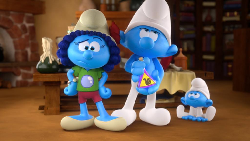 Auf dem Boden sitzt Baby-Schlumpf und schaut zu einem Schlumpf hoch, der ein Glasgefäss mit einem gelben Schnecken-Etikett hält.