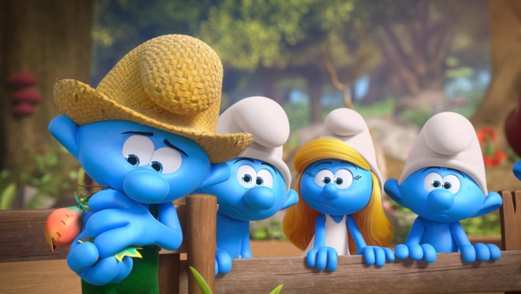 Ein Schlumpf mit Strohhut hält schützend seine Hände um eine kleine Topfpflanze mit einer orangenen, papageienschnabelförmigen Blüte. Drei Schlümpfe neben ihm schauen verwundert.