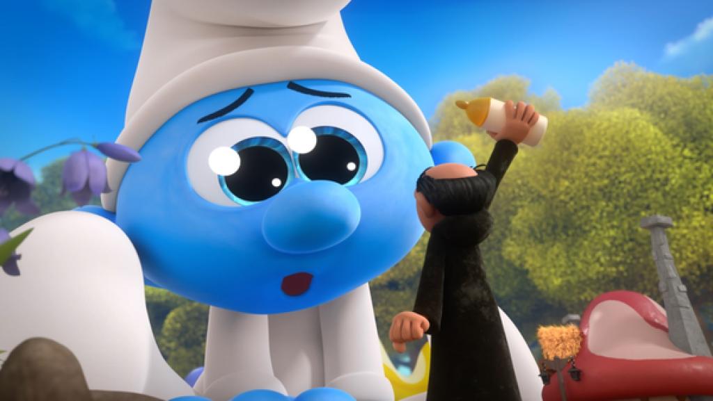 Gagamel hebt eine Nuckelflasche zum doppelt so großen Baby Schlumpf hoch, der vor ihm auf dem Boden sitzt und ihn mit großem Augen anschaut.