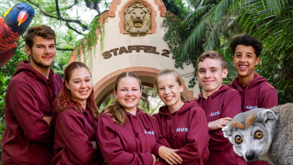 Elefant, Tiger & Kids | Rechte: MDR/Cine Impuls Leipzig GmbH/Anika Dollmeyer Sechs Teilnehmer in roten Hoodies lächeln in die Kamera. Im Hintergrund ist die Toraufschrift Staffel 2 zu erkennen.