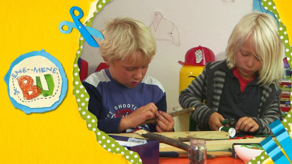 Casper und Linus bauen aus Kronkorken, Draht und einem Stock eine Rassel.