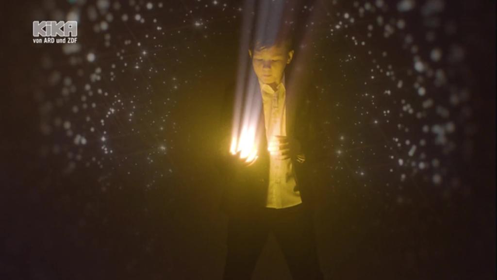 Marino Vrgoč hält eine leuchtende Kugel. Um ihn herum fliegen kleine Partikel.