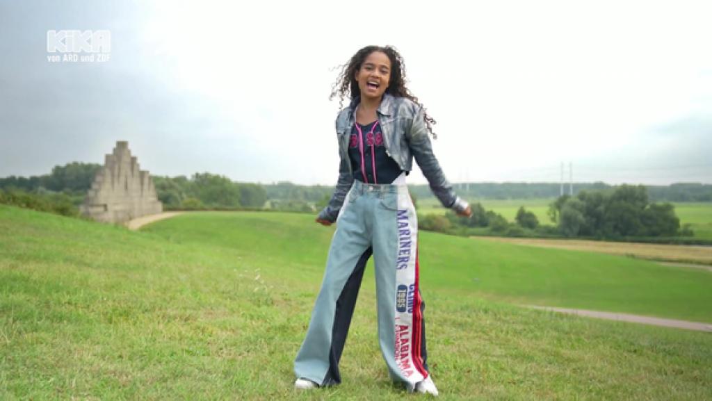 Meadow singt und tanzt auf einer grünen Wiese.