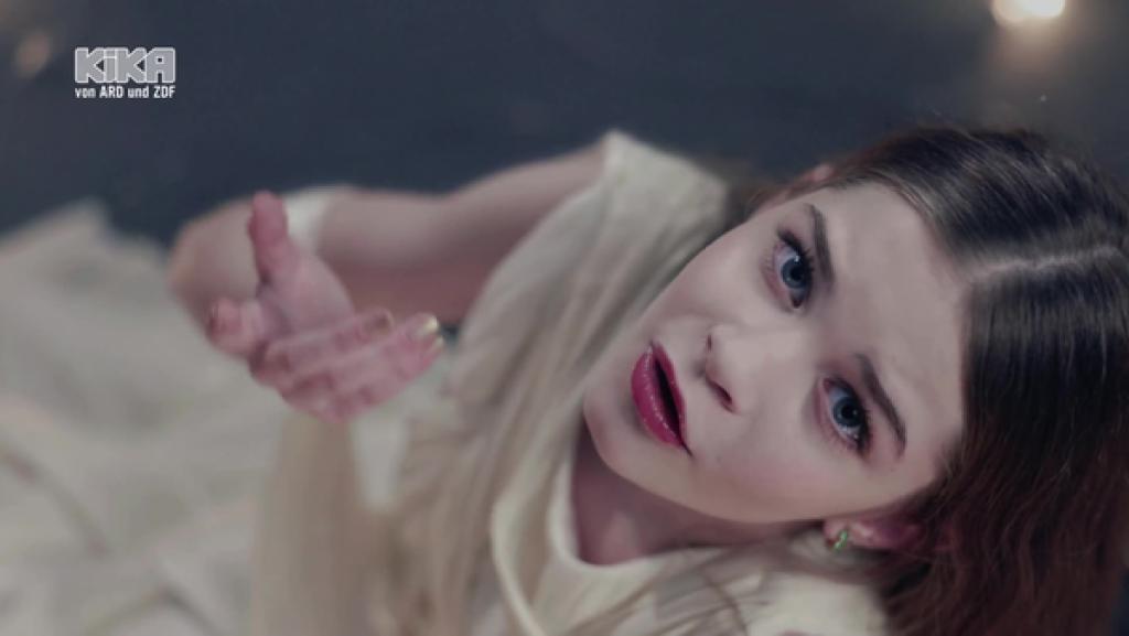 Nela Mancheska singt. Sie sitzt auf dem Boden und blickt hoch in die Kamera.